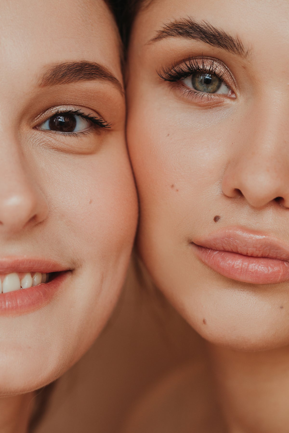 Close-up of two women's faces side by side, focusing on their eyes and lips. One smiles softly; the other has a neutral expression. Warm, intimate tone.