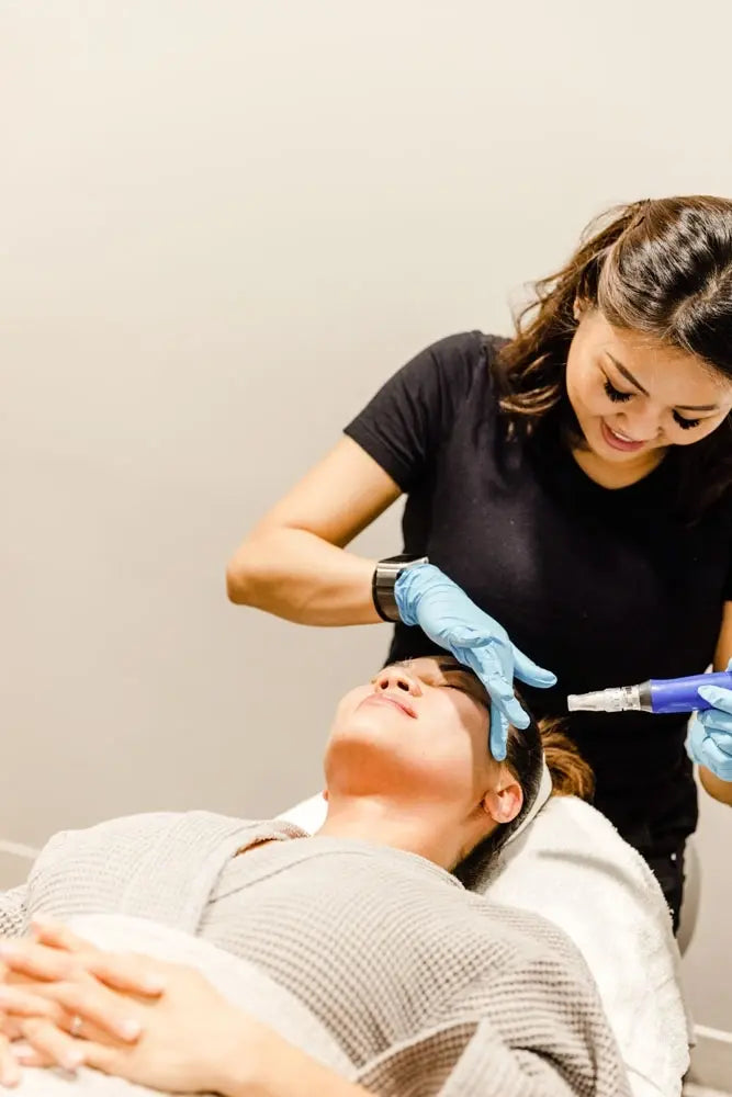 Esthetician performing a microneedling treatment on a client