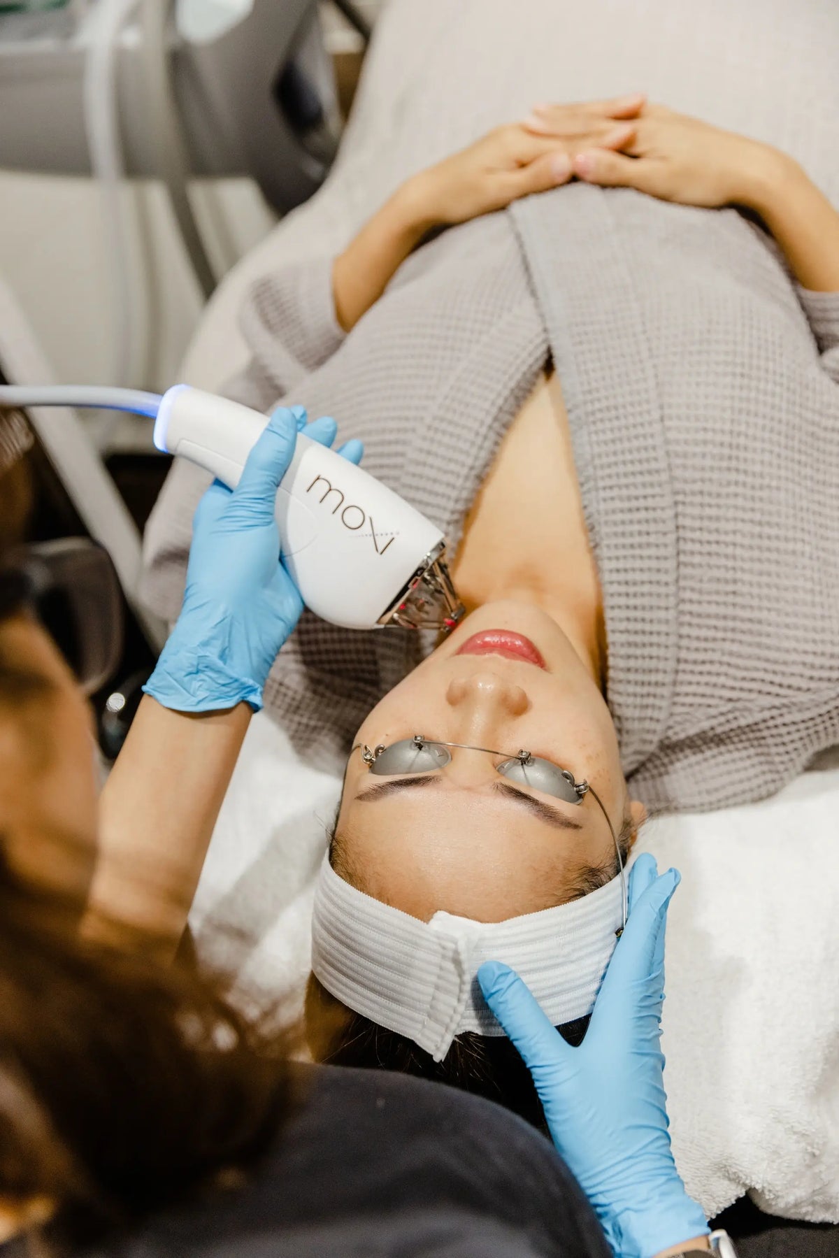 Practitioner using the Moxi laser device on a client’s face